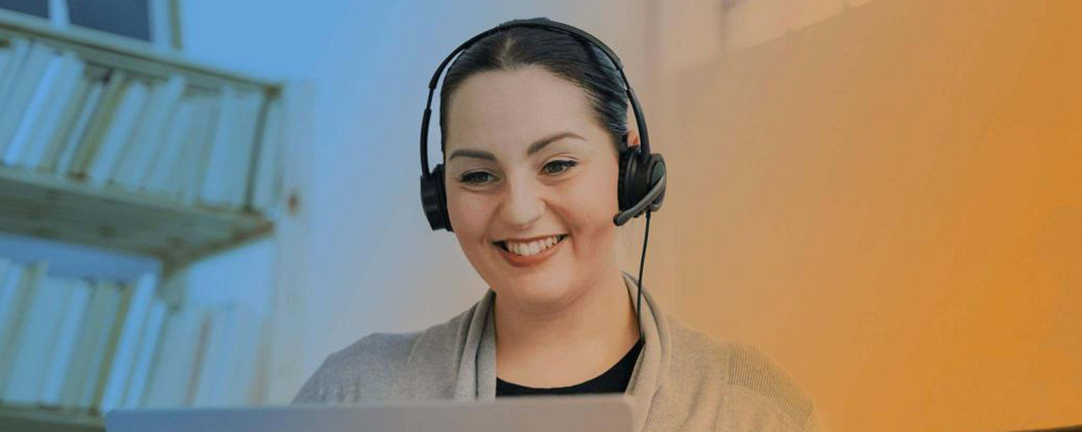Remote worker wearing a headset and smiling at their screen.
